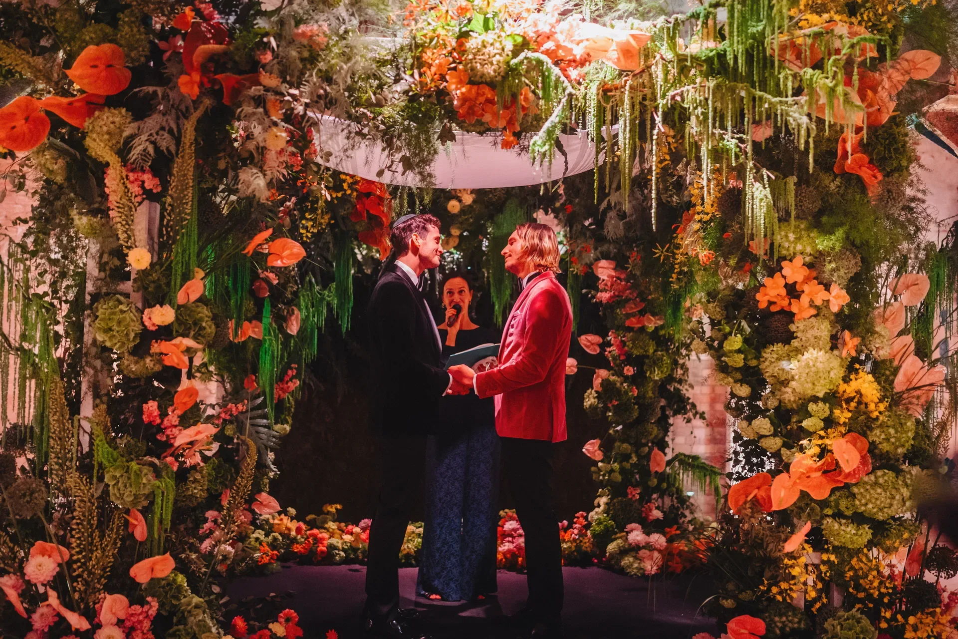 Shaun and Hendrik exchanging vows beneath the floral arch at DEEP Berlin